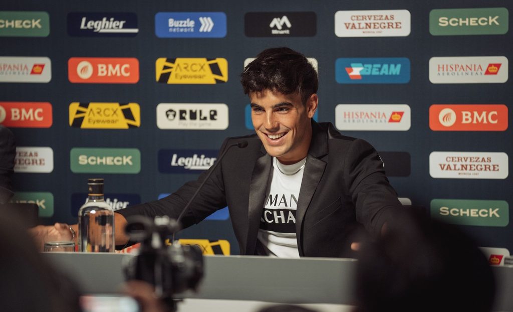 Óscar Casas en una escena de la serie de HBO Pollos sin cabeza. Aparece en una sala de prensa de un estadio de fútbol con publicidad al fondo.